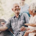 Group of older adults smiling and laughing together outdoors, representing restored confidence and quality of life after dental implant treatment.