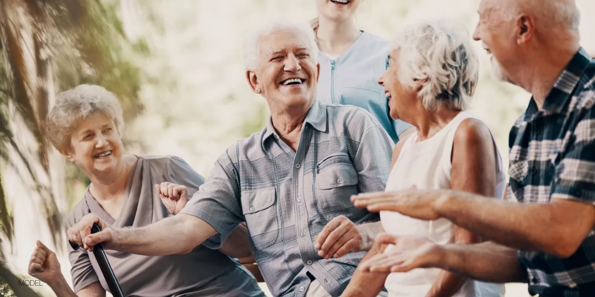 Group of older adults smiling and laughing together outdoors, representing restored confidence and quality of life after dental implant treatment.